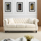 Beige velvet three-seater sofa with rolled-up armrests and rivet decorations; seats 3 people.