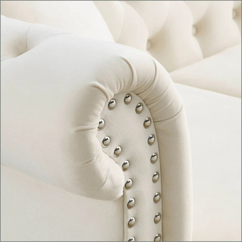 Beige velvet three-seater sofa with rolled-up armrests and rivet decorations; seats 3 people.