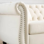 Beige velvet three-seater sofa with rolled-up armrests and rivet decorations; seats 3 people.