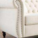 Beige velvet three-seater sofa with rolled-up armrests and rivet decorations; seats 3 people.