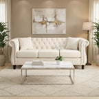 Beige velvet three-seater sofa with rolled-up armrests and rivet decorations; seats 3 people.