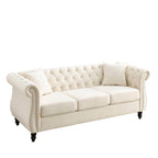 Beige velvet three-seater sofa with rolled-up armrests and rivet decorations; seats 3 people.